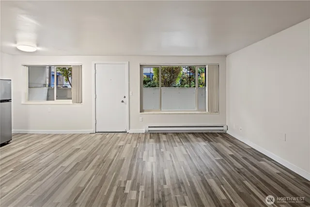 an empty room with wooden floor and windows