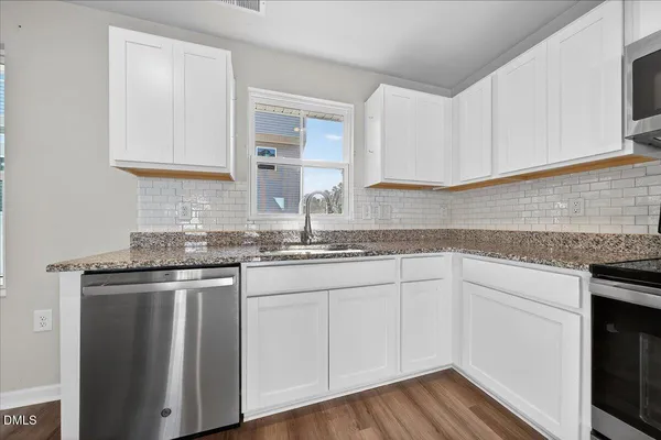 a kitchen with granite countertop white cabinets and a sink
