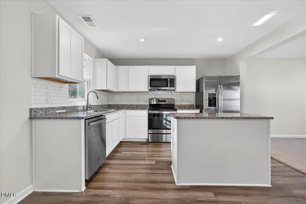 a kitchen with granite countertop a refrigerator stove top oven and sink