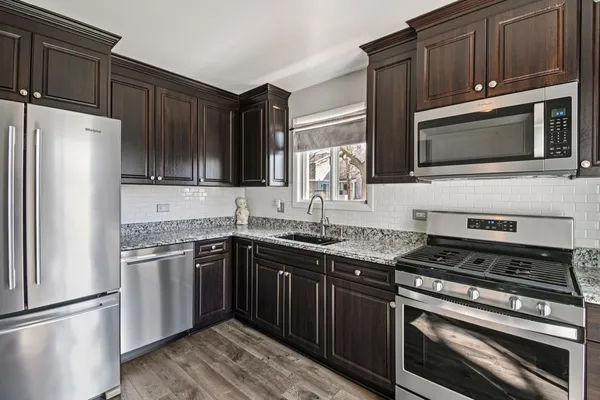 a kitchen with granite countertop a sink stove and refrigerator