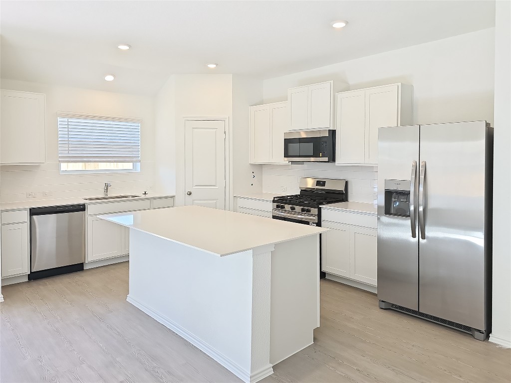 1117 Nesting Bird Drive Georgetown, TX 78628 - Photo 6 of 20 a kitchen view with stainless steel appliances a refrigerator a sink a stove a microwave a counter top and white cabinets
