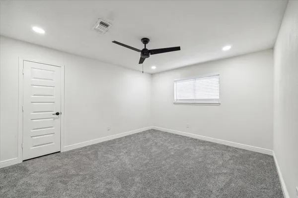 an empty room with a ceiling fan and window