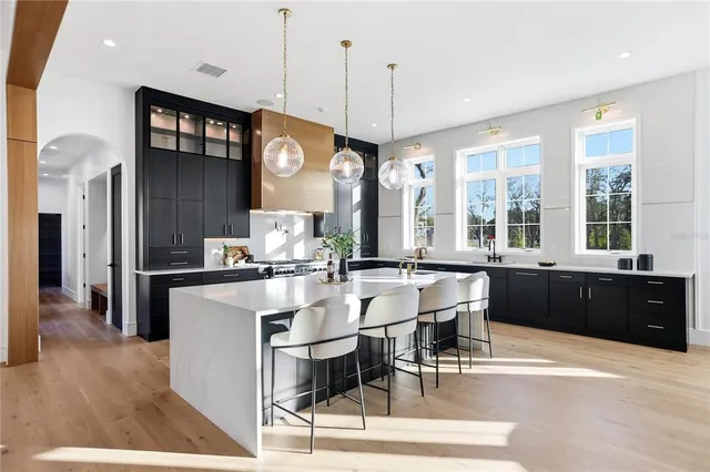 a large kitchen with a large counter top a sink a stove and cabinets