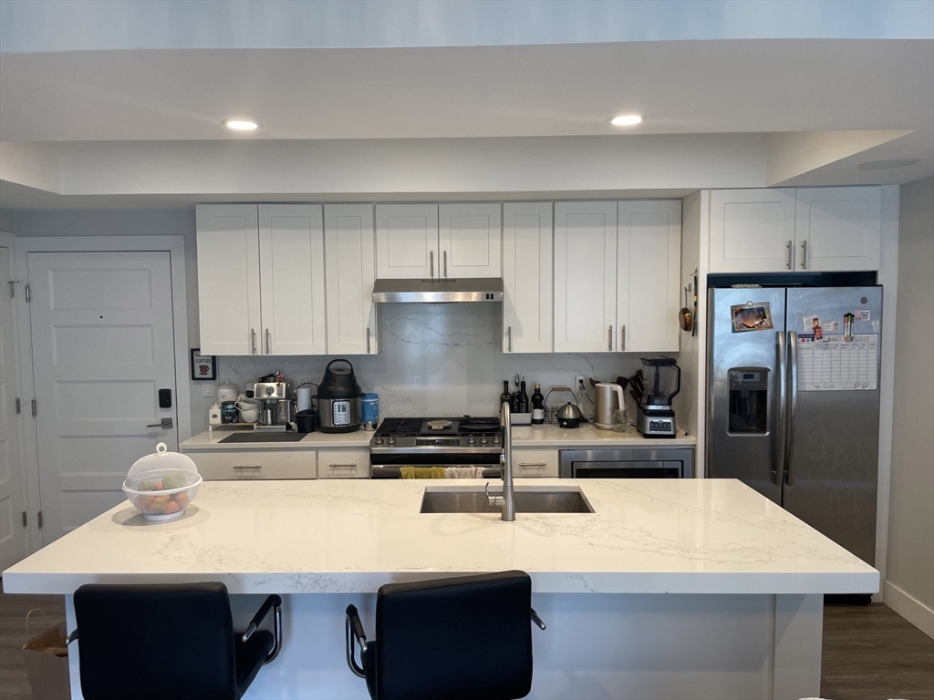 151 Hancock Street, Unit 5 Quincy, MA 02171 - Photo 3 of 12 a kitchen with kitchen island granite countertop a sink a stove and refrigerator