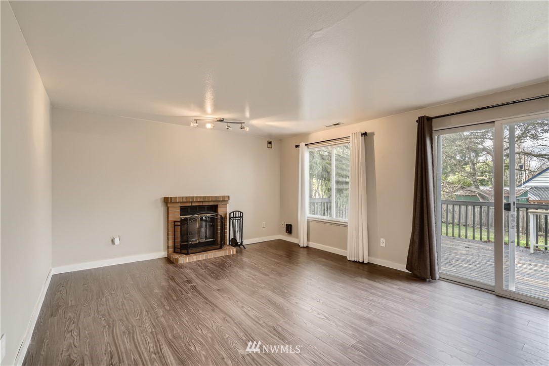 5445 17th Avenue Southwest Seattle, WA 98106 - Photo 3 of 19 an empty room with wooden floor fireplace and windows