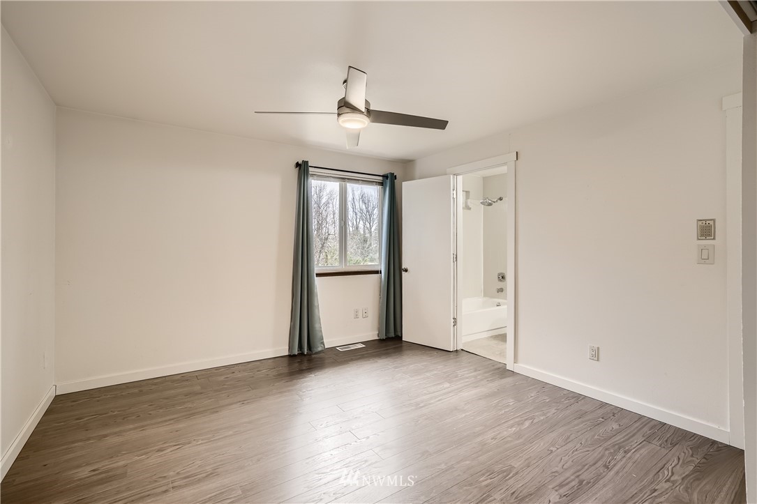 5445 17th Avenue Southwest Seattle, WA 98106 - Photo 10 of 19 an empty room with wooden floor ceiling fan and windows