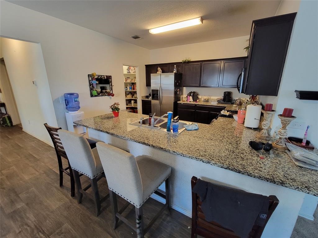 3610 Batson Drive Austin, TX 78725 - Photo 12 of 30 a kitchen with granite countertop kitchen island stainless steel appliances a sink a stove a table and chairs