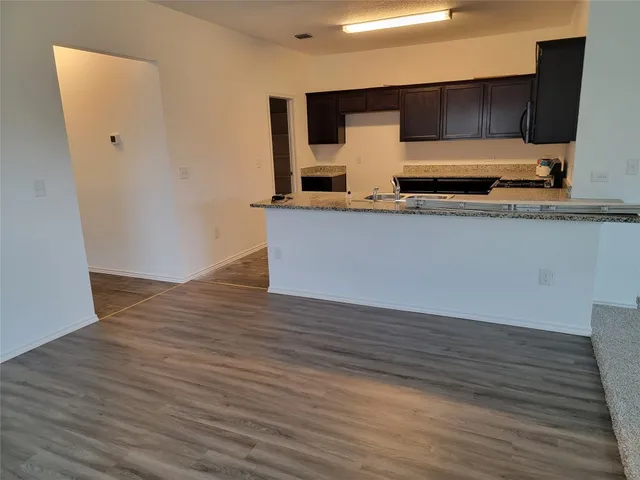 a view of kitchen with wooden floor and cabinets