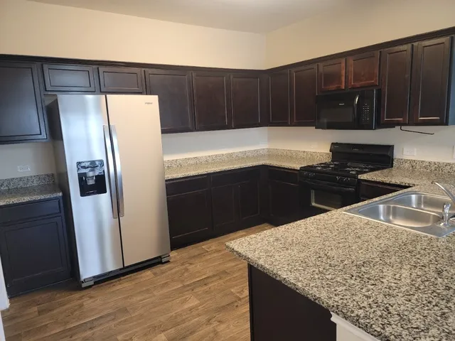 a kitchen with granite countertop a refrigerator and a sink