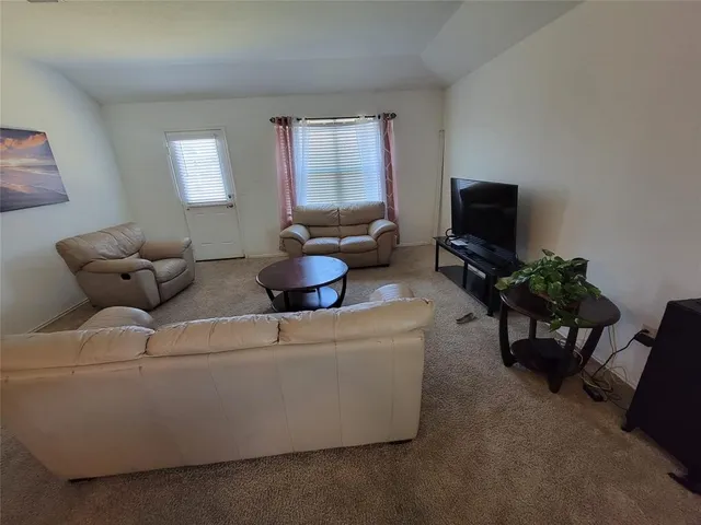 a living room with furniture a flat screen tv and a window