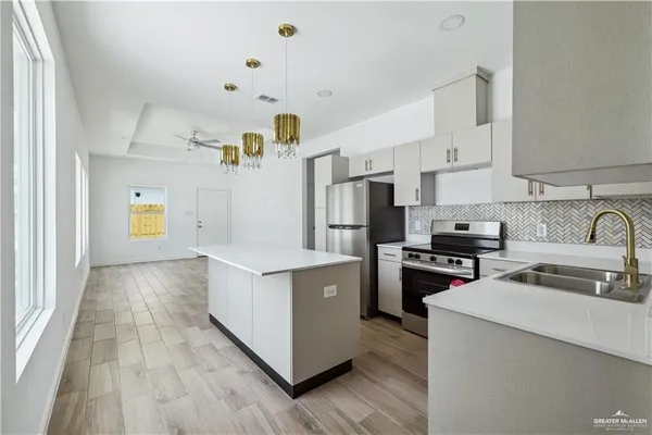 a kitchen with a sink a counter top space stainless steel appliances and cabinets