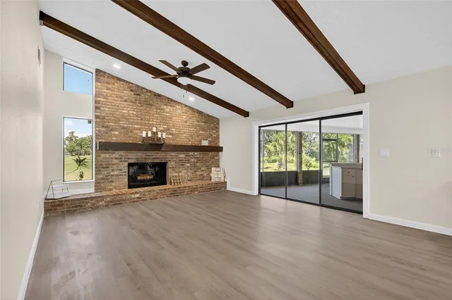 a view of an empty room with wooden floor and a ceiling fan