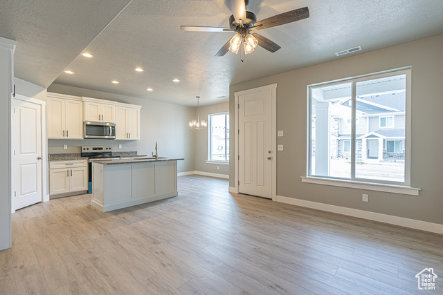 2242 South 1120 West, Unit 69 Logan, UT 84321 - Photo 6 of 26 Kitchen with an island with sink, a textured ceiling, recessed lighting, appliances with stainless steel finishes, and light wood-style flooring