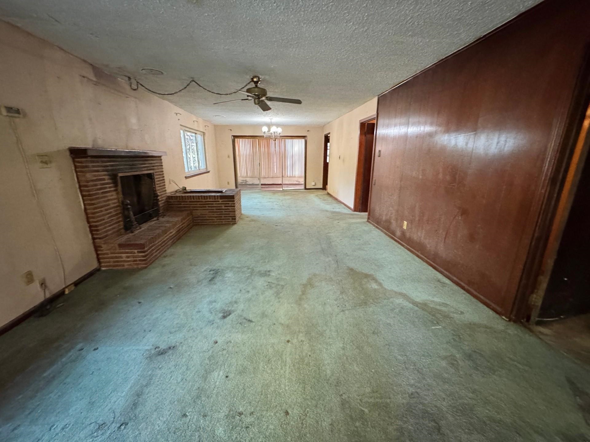 3085 Hoskins Road Memphis, TN 38111 - Photo 5 of 14 Unfurnished living room with a fireplace, a ceiling fan, a textured ceiling, and carpet