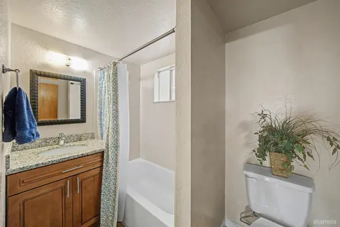 a bathroom with a granite countertop sink a toilet and a mirror