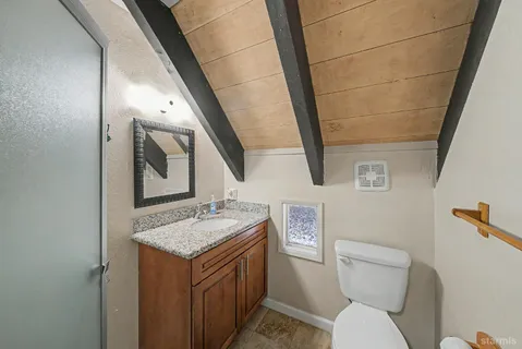 a bathroom with a granite countertop toilet sink and mirror