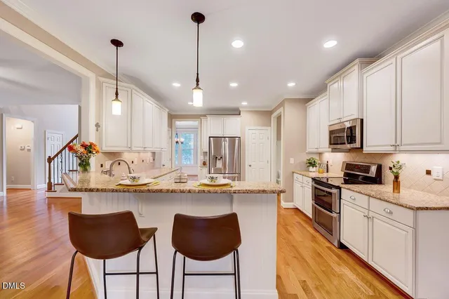 a view of a livingroom with wooden floor a ceiling fan and windows