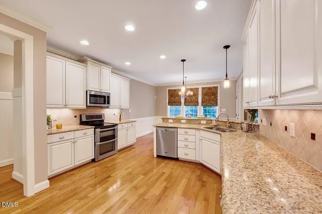 a kitchen with granite countertop white cabinets appliances and a window