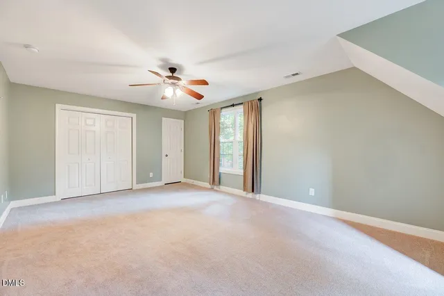 an empty room with windows and chandelier fan