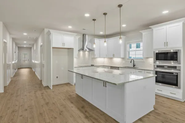 a large kitchen with stainless steel appliances kitchen island a large counter top a stove a refrigerator and a sink