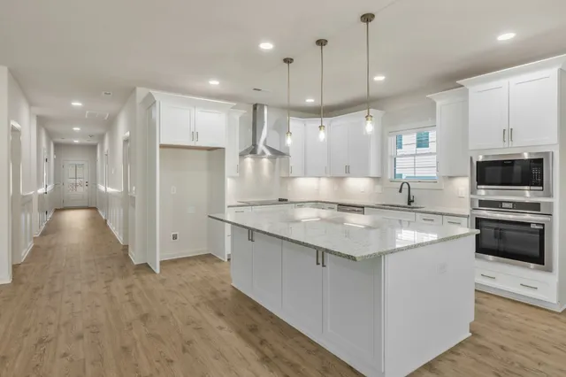 a large kitchen with stainless steel appliances kitchen island a large counter top a stove a refrigerator and a sink