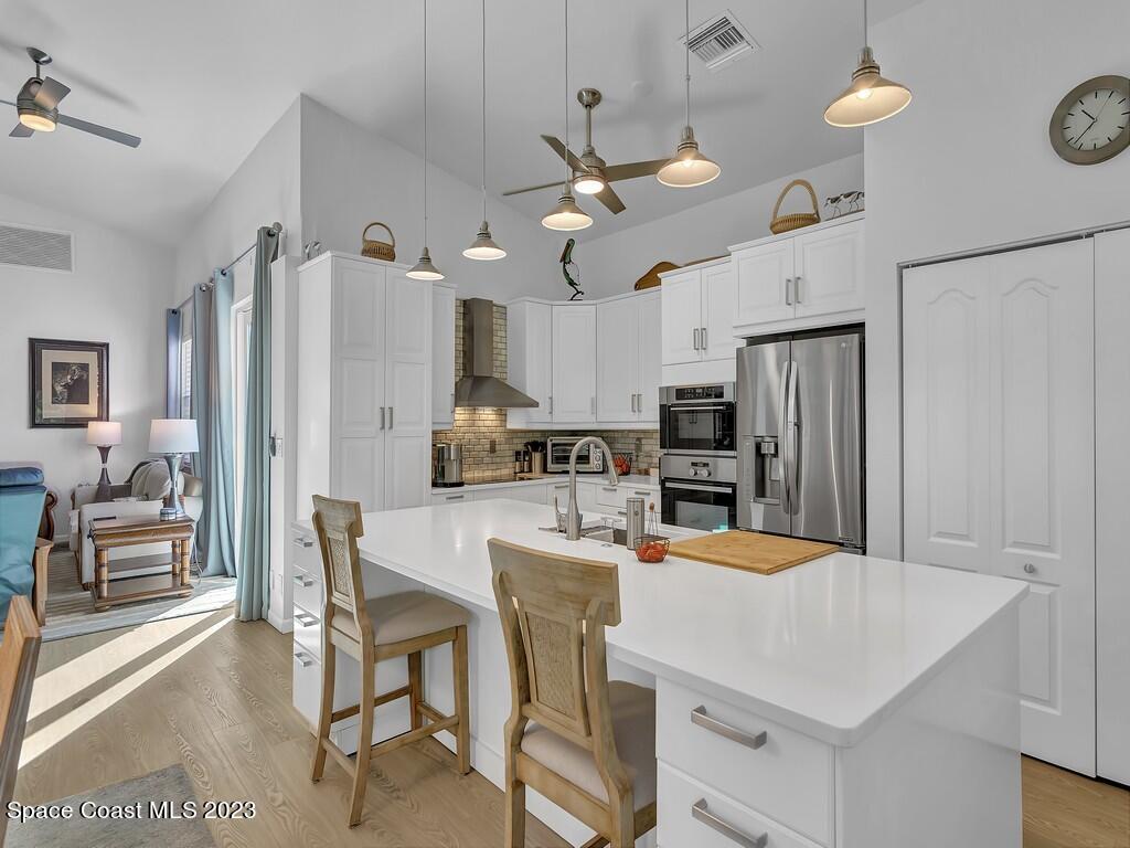 5621 Spanish River Road Fort Pierce, FL 34951 - Photo 9 of 34 a kitchen with stainless steel appliances kitchen island granite countertop a refrigerator a stove top oven a sink dishwasher and white cabinets with wooden floor
