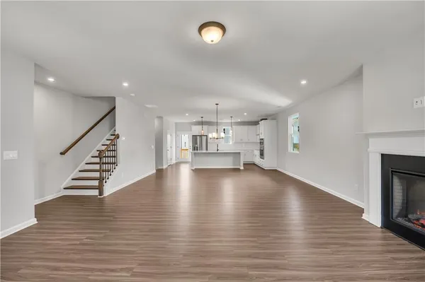 a view of an empty room with wooden floor fireplace and windows
