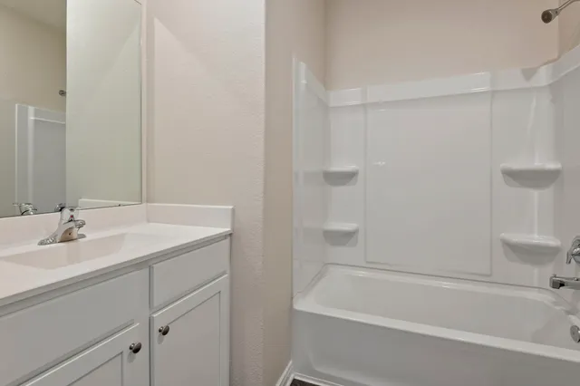 a bathroom with a granite countertop sink and a bathtub