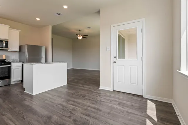 an empty room with wooden floor and a kitchen