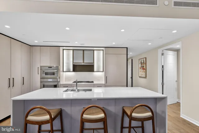 a kitchen with stainless steel appliances granite countertop a table chairs sink and cabinets