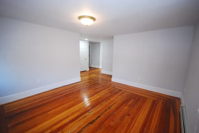 a view of empty room with window and wooden floor