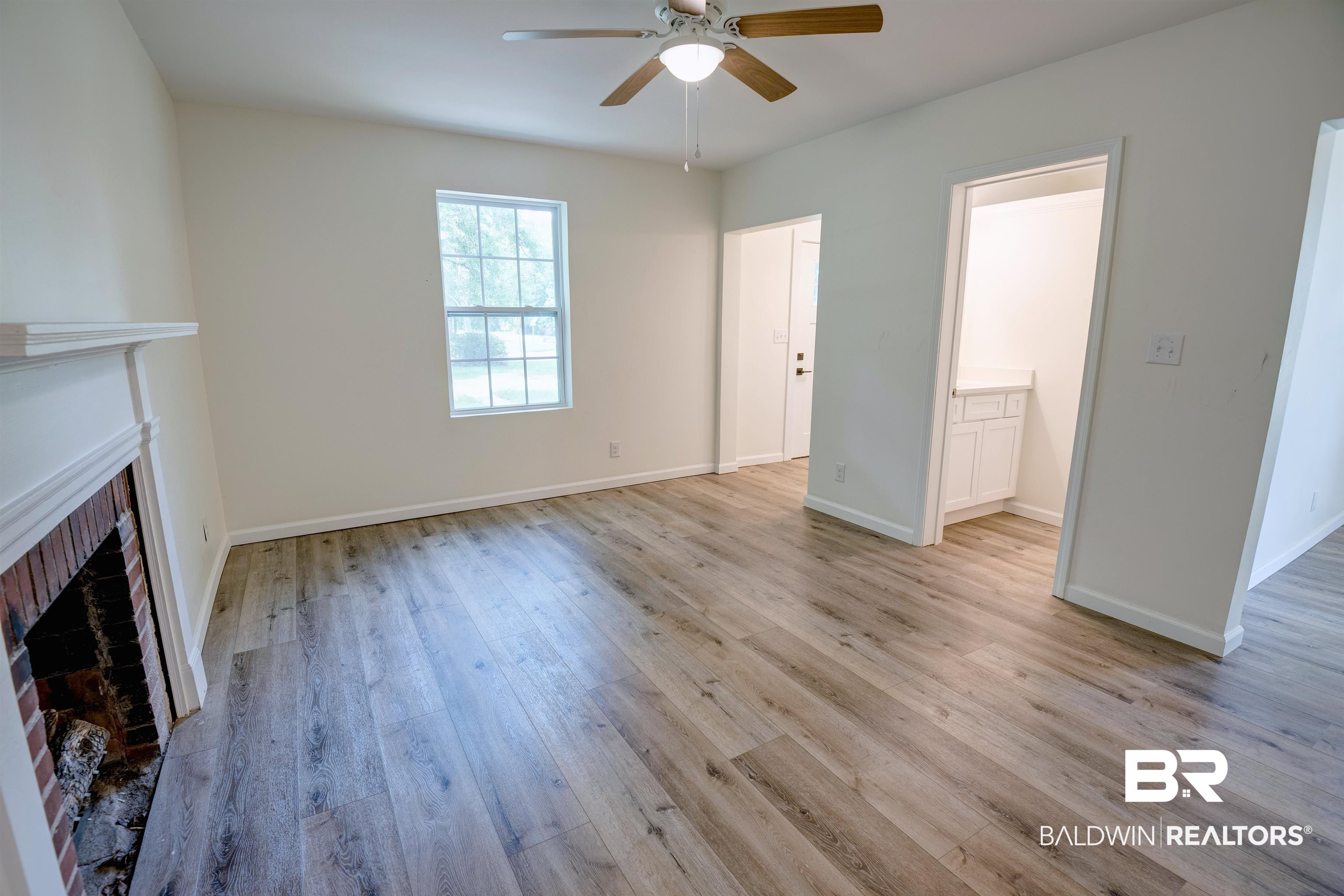 510 East Myrtle Avenue Foley, AL 36535 - Photo 6 of 22 Unfurnished living room with a brick fireplace, a ceiling fan, and light wood-style flooring