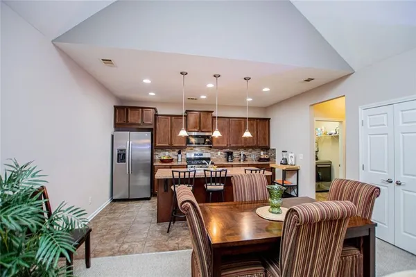 a kitchen with stainless steel appliances granite countertop a table chairs sink and cabinets