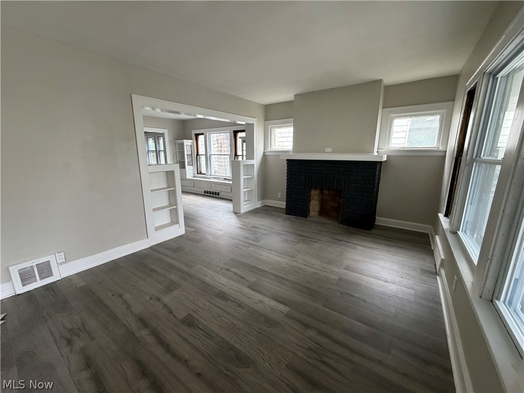 15317 Shiloh Road Cleveland, OH 44110 - Photo 4 of 29 Spacious room featuring wood-finish flooring, a black brick fireplace with a white mantel, and multiple windows