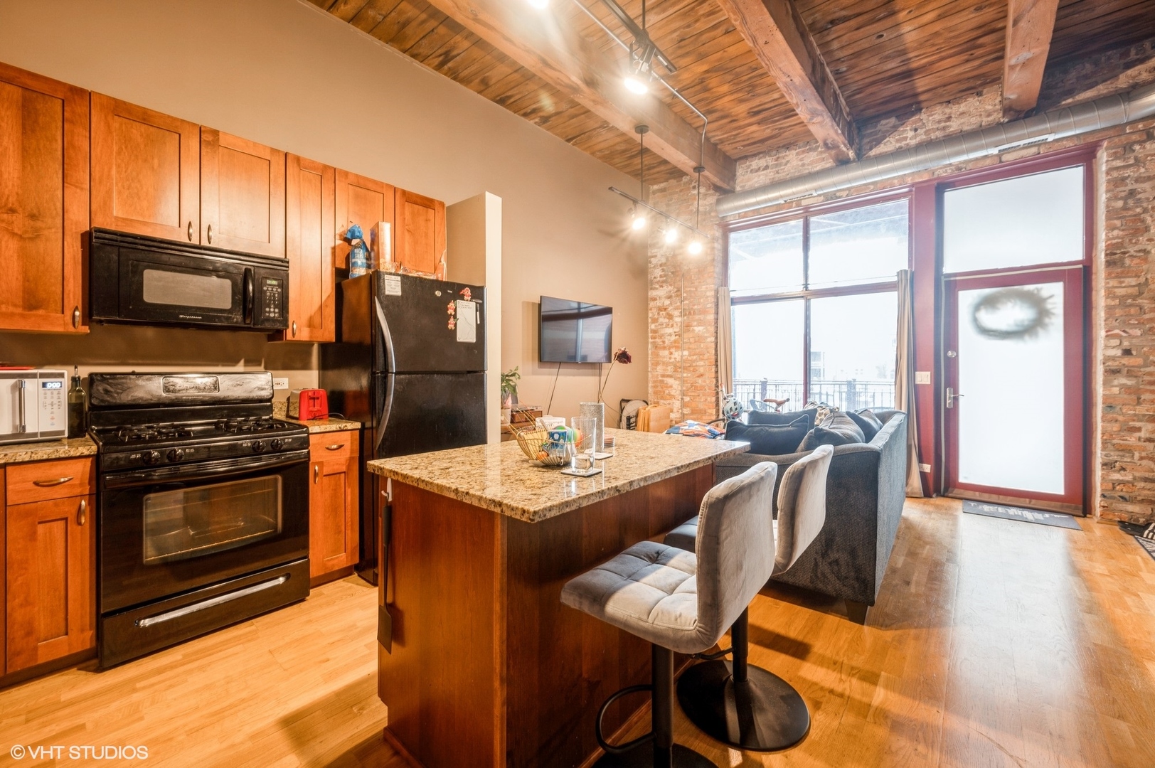 1061 West 16th Street, Unit 201 Chicago, IL 60608 - Photo 5 of 14 a kitchen with stainless steel appliances a stove a refrigerator a sink a dining table and chairs with wooden floor