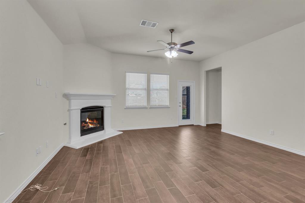 3106 Maverick Drive Forney, TX 75126 - Photo 7 of 29 an empty room with windows fireplace and fan