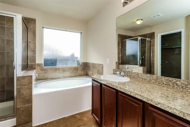 a bathroom with a granite countertop sink and a bathtub