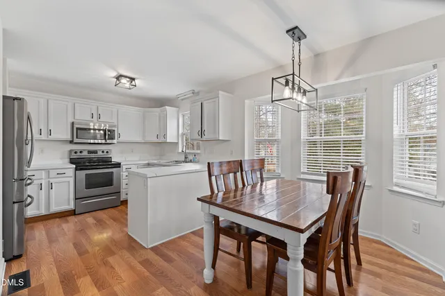 a kitchen with stainless steel appliances a dining table chairs stove refrigerator and microwave