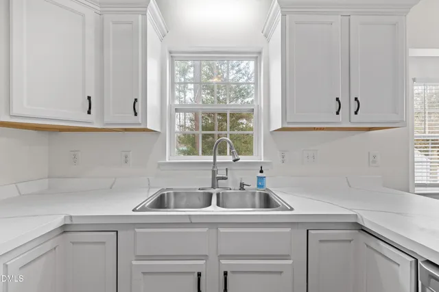 a kitchen with white cabinets and a window