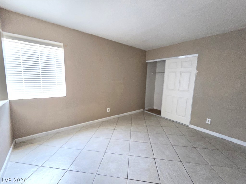 2882 Sandyfalls Way Las Vegas, NV 89142 - Photo 13 of 18 A well-lit bedroom featuring durable tiled flooring and a convenient sliding closet door.