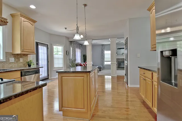a kitchen with stainless steel appliances granite countertop a sink a stove and a wooden floors