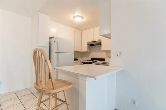 a kitchen with a sink a refrigerator and chairs