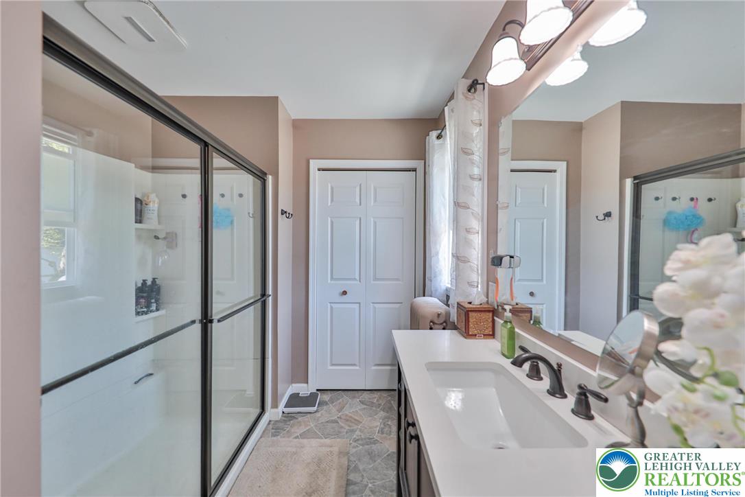 417 3rd Street Lehighton, PA 18235 - Photo 10 of 39 This primary bathroom features a shower with sliding glass doors, a single vanity, and a large mirror.