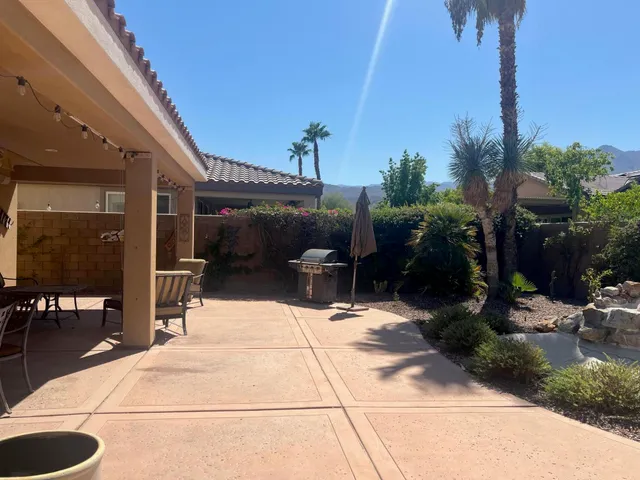 a view of a patio with table and chairs in front of house