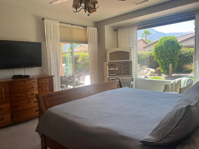 a bedroom with a bed and a flat tv screen on dresser