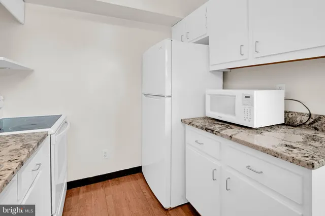a kitchen with granite countertop white cabinets and white appliances