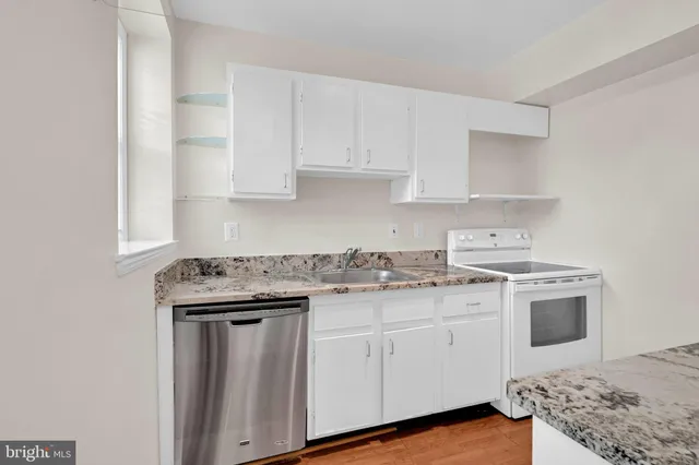 a kitchen with granite countertop white cabinets and white appliances