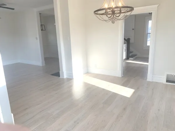 a view of a hallway with wooden floor and chandelier