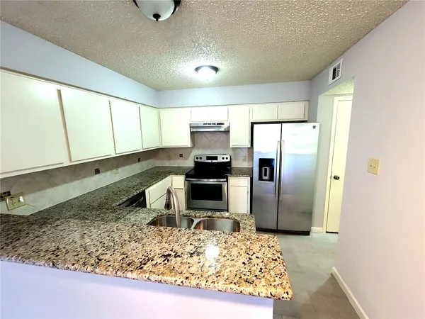 a kitchen with a refrigerator sink and wooden cabinets