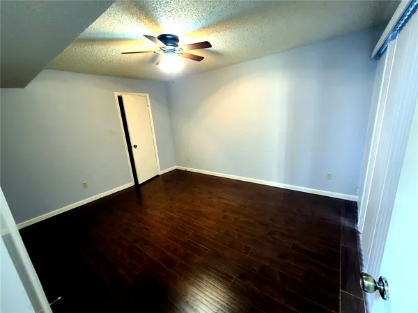 an empty room with wooden floor and fan
